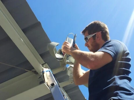Tecnico installa una telecamera di videosorveglianza su una struttura esterna sotto il sole