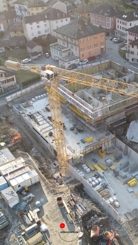 Ripresa dall’alto di un cantiere in costruzione con gru e strutture in cemento armato, in centro abitato urbano